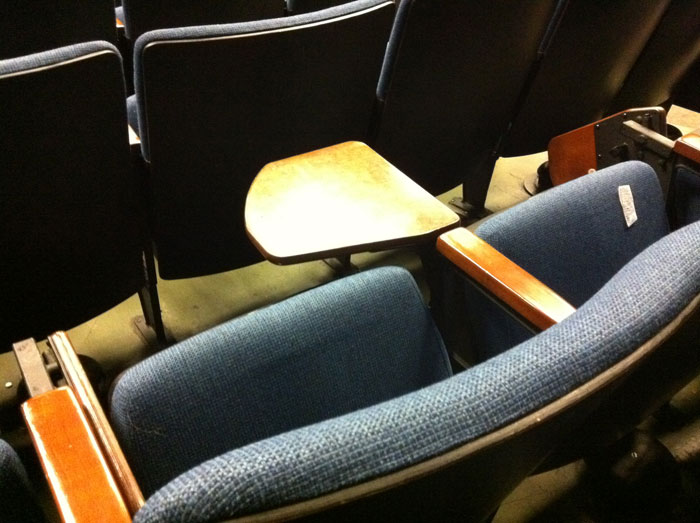 Lecture hall auditorium seat with a tiny foldout 'desk' the size of an iPad